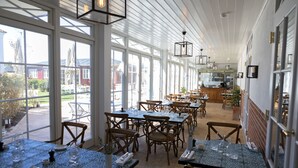 A spacious indoor dining area with large windows, wooden tables, and chairs. - Strandhotellet - Blokhus (Blokhus)