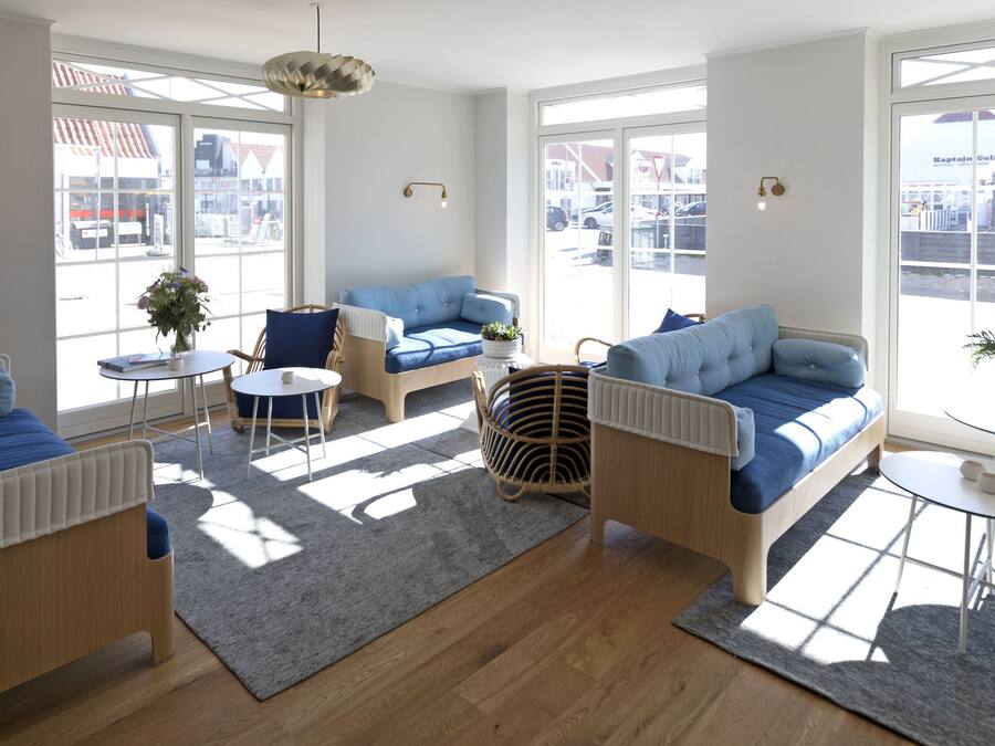 Ein helles Wohnzimmer mit einem blauen Sofa, einem Holztisch und einem Korbstuhl.