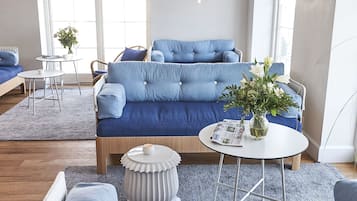 Ett modernt vardagsrum med en blå soffgrupp, ett vitt soffbord och en vas med blommor.