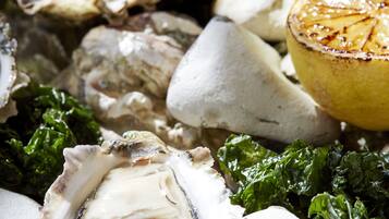 A close-up of oysters, lemon, and greens.