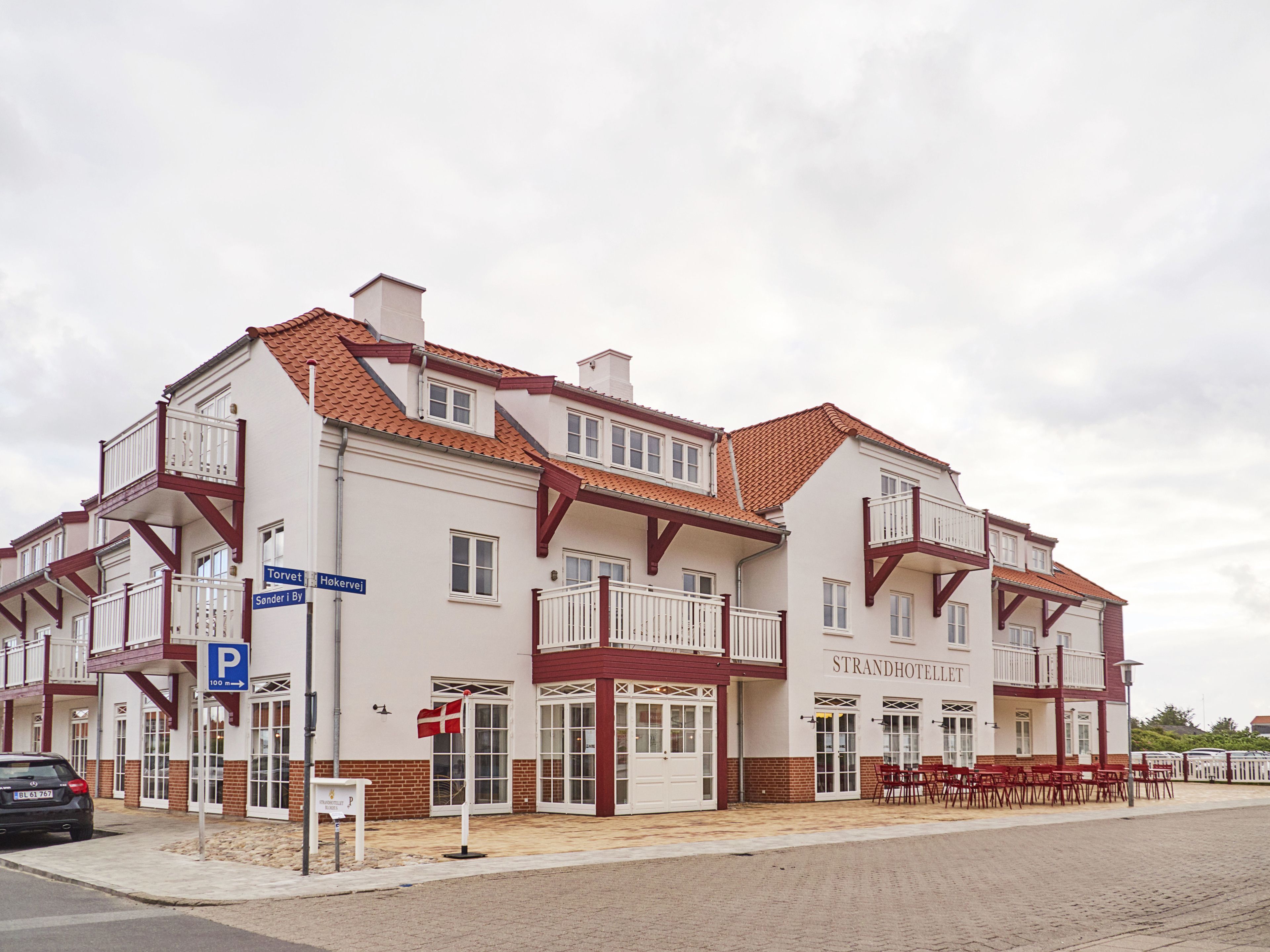 A two-story building with a sign reading "STRANDHOTELLET" and a visible parking sign.