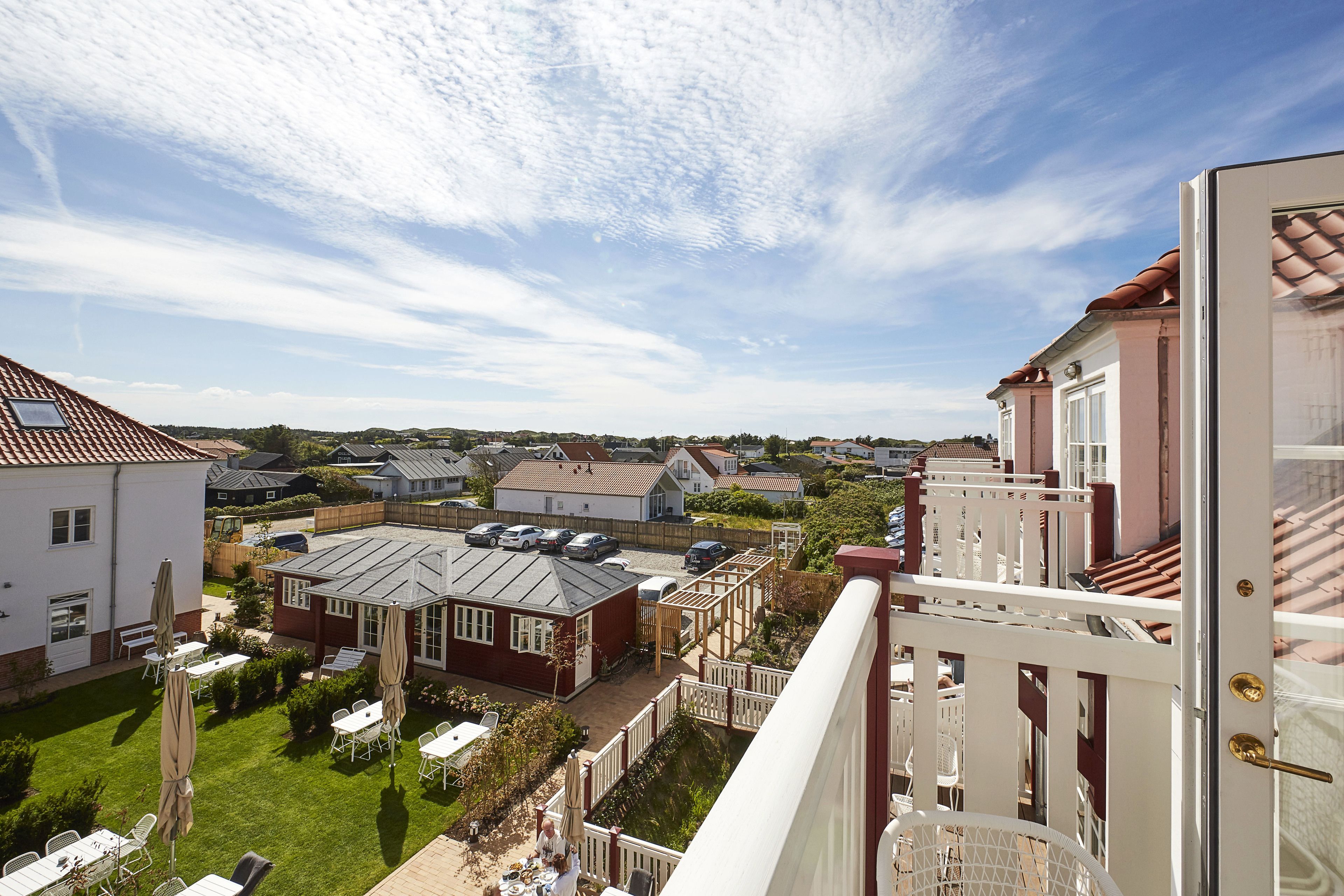 Zona residencial con vistas a casas, un patio con mobiliario exterior y cielo despejado.
