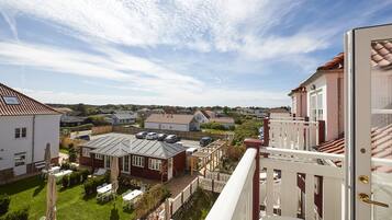 Zona residencial con vistas a casas, un patio con mobiliario exterior y cielo despejado.