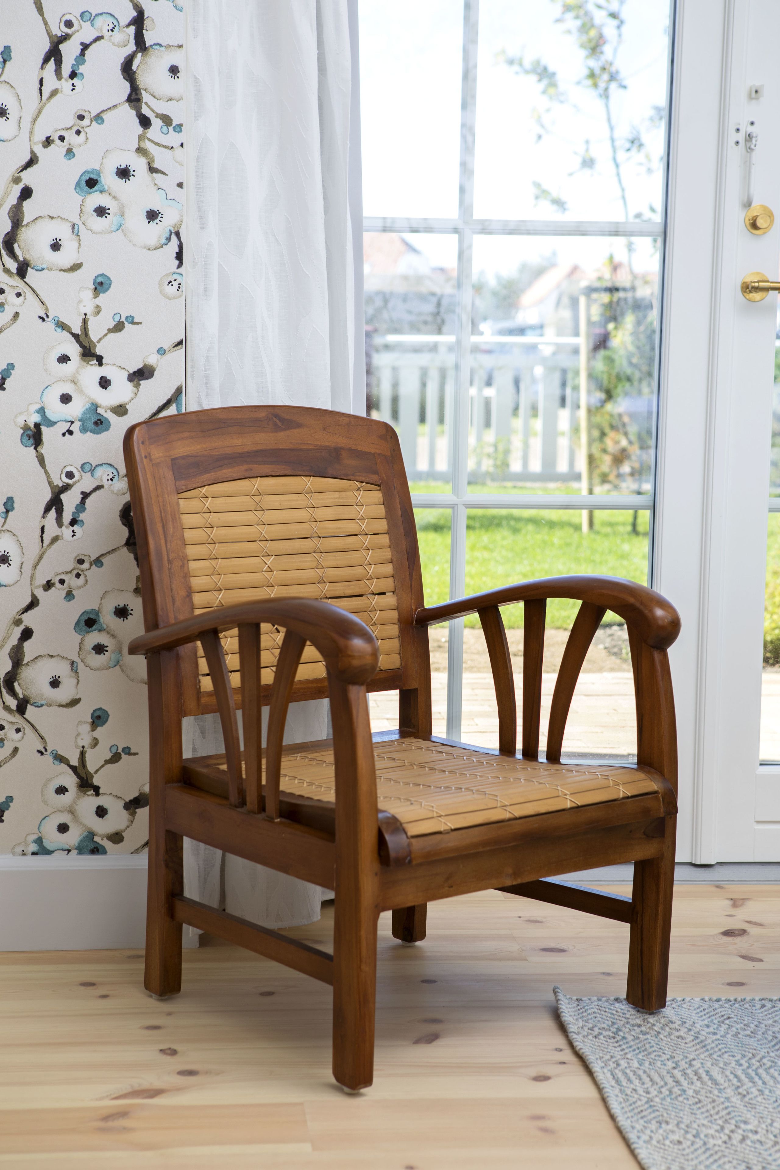 Une chaise en bois, dotée d’un dossier et d’une assise en osier, placée devant une porte en verre à cadre blanc.