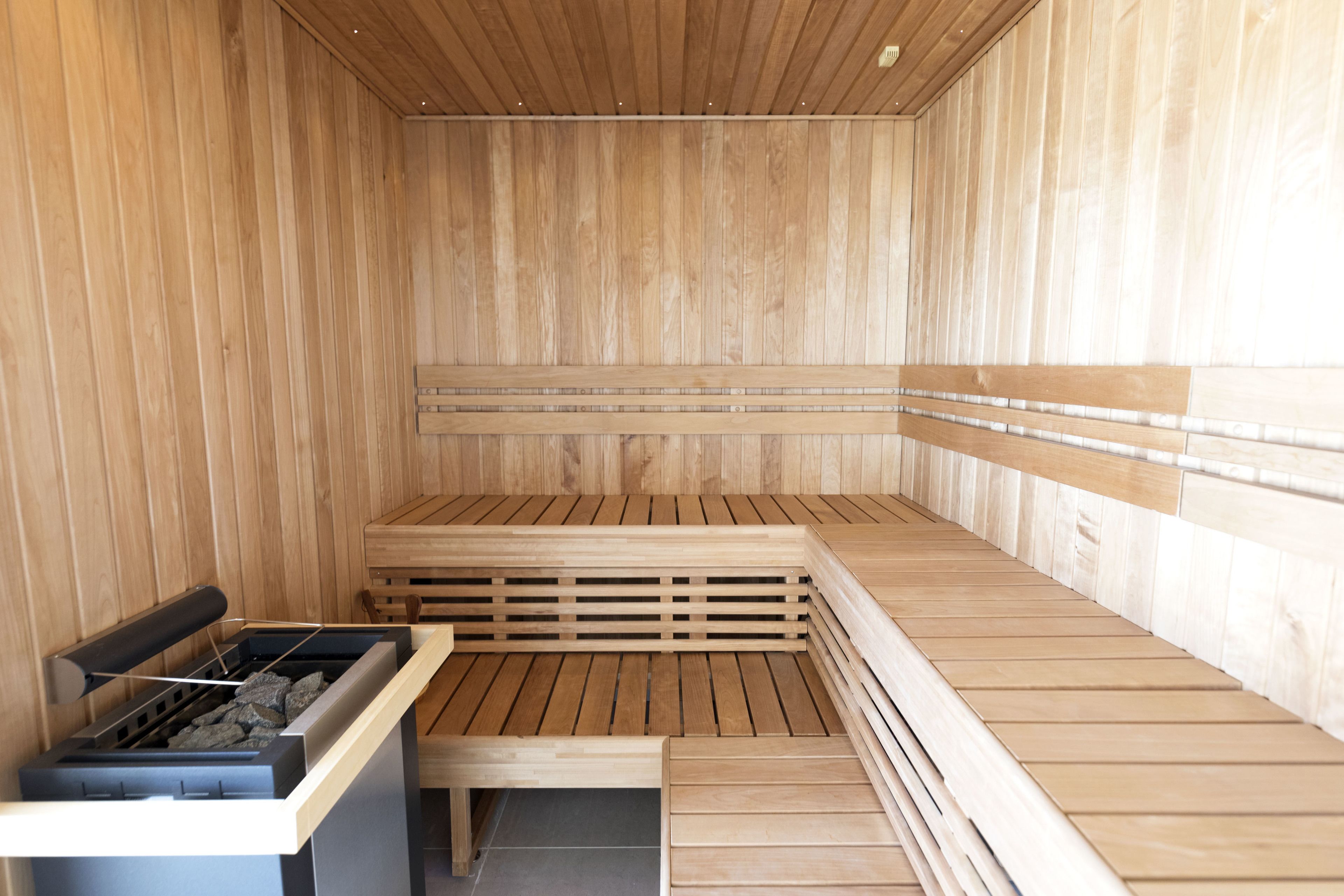Sauna, jossa on puiset lauteet ja kivinen allas.