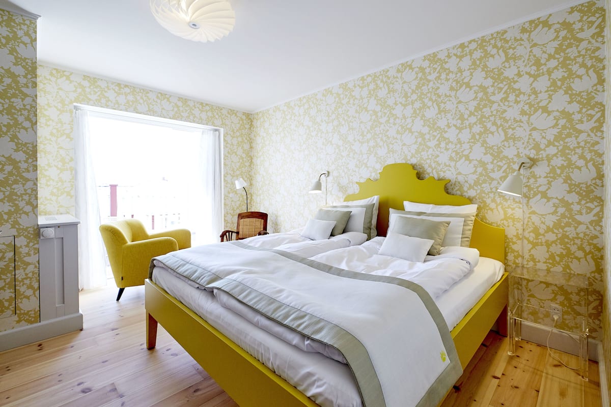A bedroom with a bed, a chair, and a window.