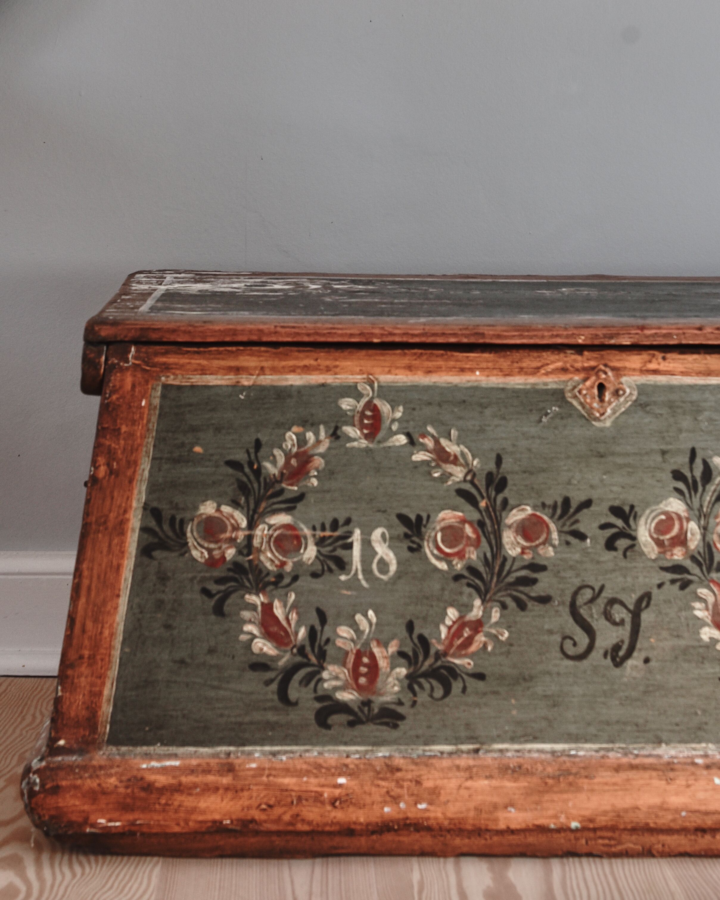 Un cofre de madera antiguo con diseños florales y el número '18' y las iniciales 'S.J.'