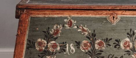 Un cofre de madera antiguo con diseños florales y el número '18' y las iniciales 'S.J.'