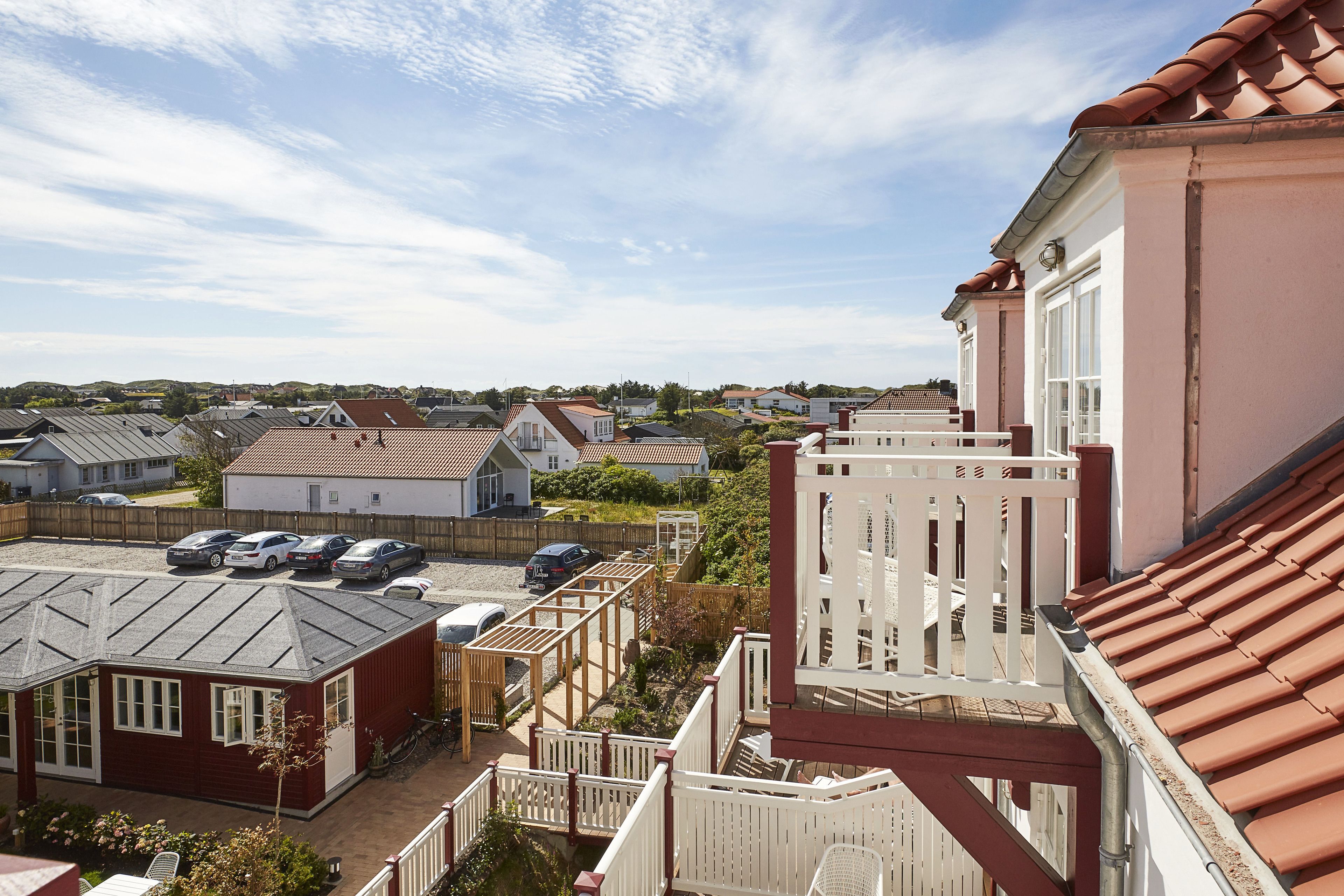 A residential area with houses, a parking lot, and a red-roofed building.