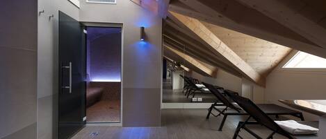 Quarto de sótão moderno e espaçoso, com teto inclinado, porta de vidro para um recanto aconchegante e poltronas reclináveis com vista para o céu.