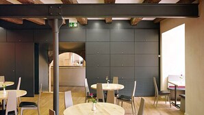 Un intérieur moderne avec des tables et des chaises rondes, un mur foncé et un panneau de signalisation indiquant la sortie, bien visible.