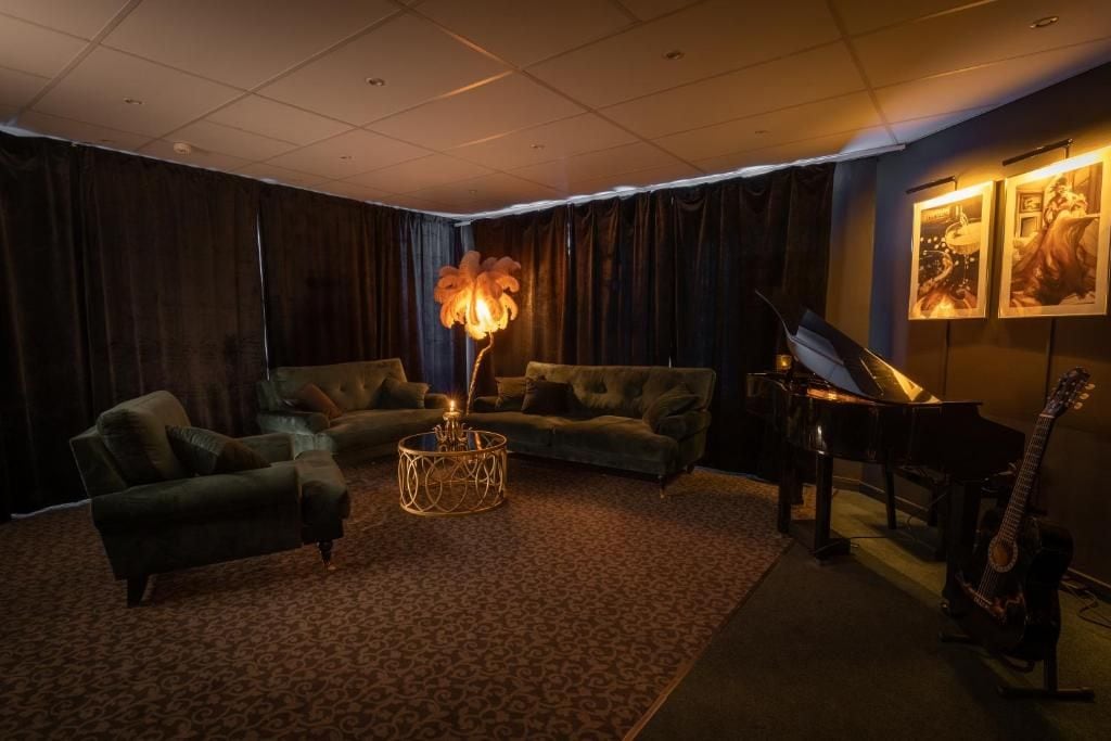 A room with a grand piano, a guitar, a sofa, and a decorative floor lamp.