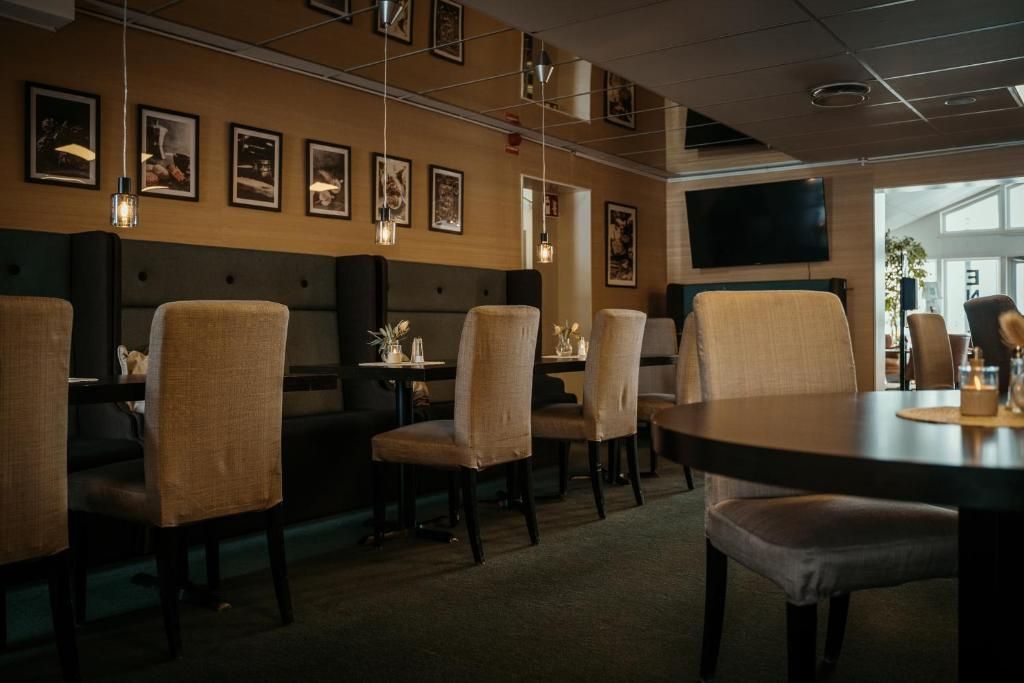 A restaurant with booths and tables, framed pictures on the wall, and a flat-screen TV.