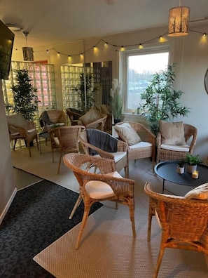 A cozy living area with wicker furniture, a round table, and a large window providing a view. - Hotel Entré Norr (Umea)