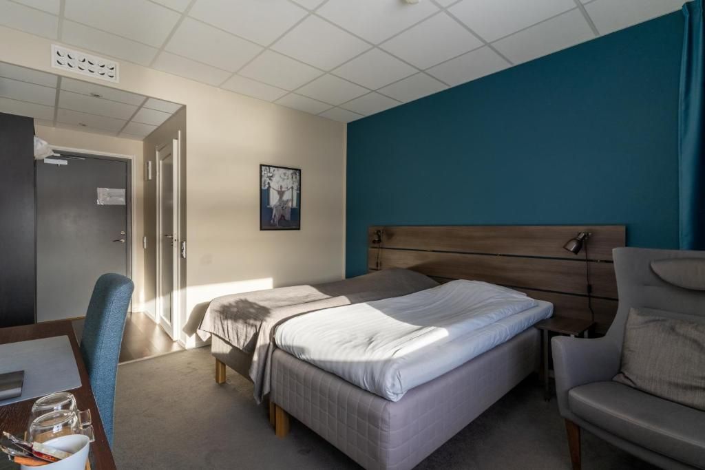 A hotel room with a bed, a desk, and a chair.