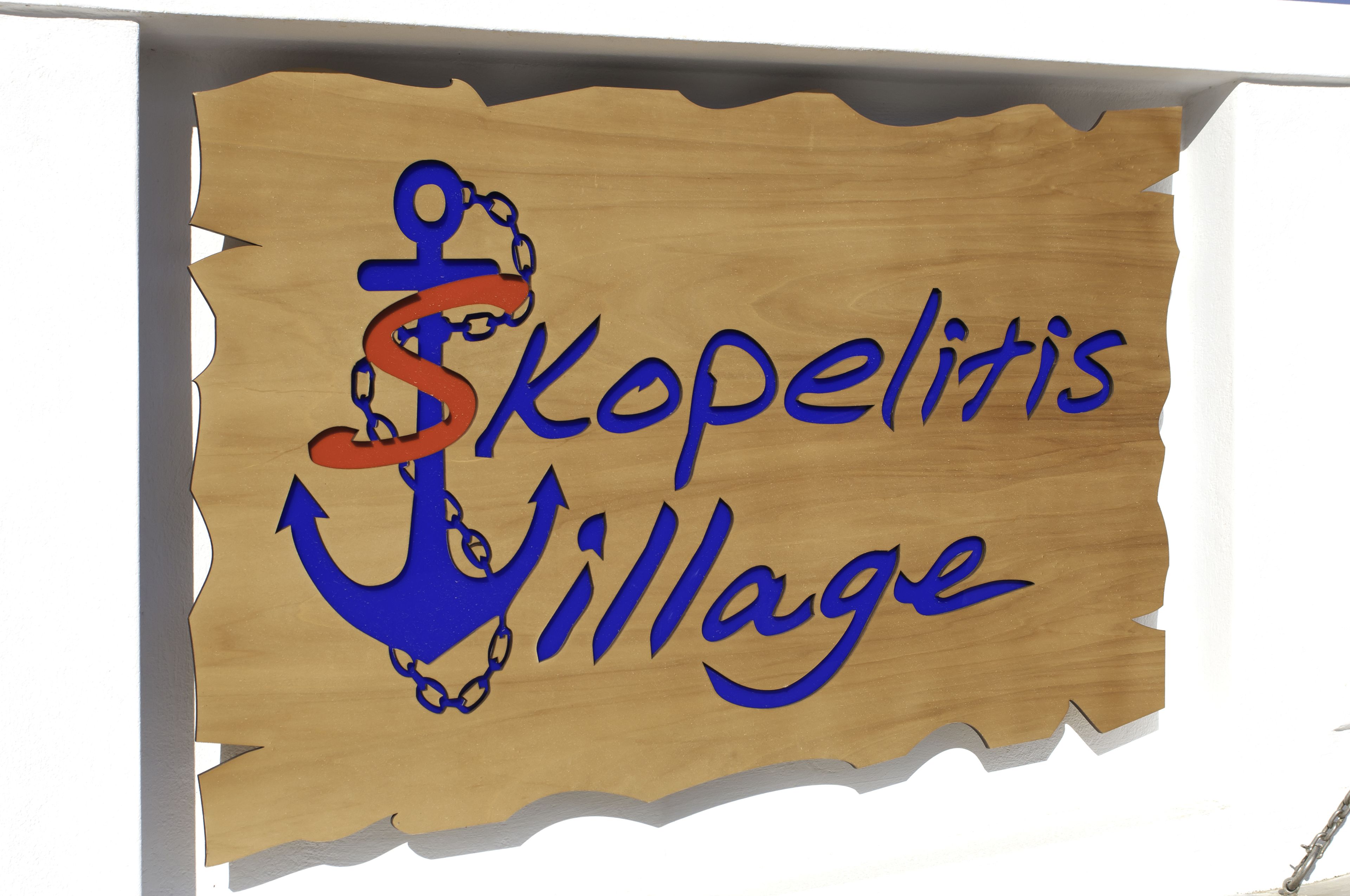 Ein hölzernes Schild mit dem Schriftzug 'Skopelitis Village' und einer Ankerdarstellung.