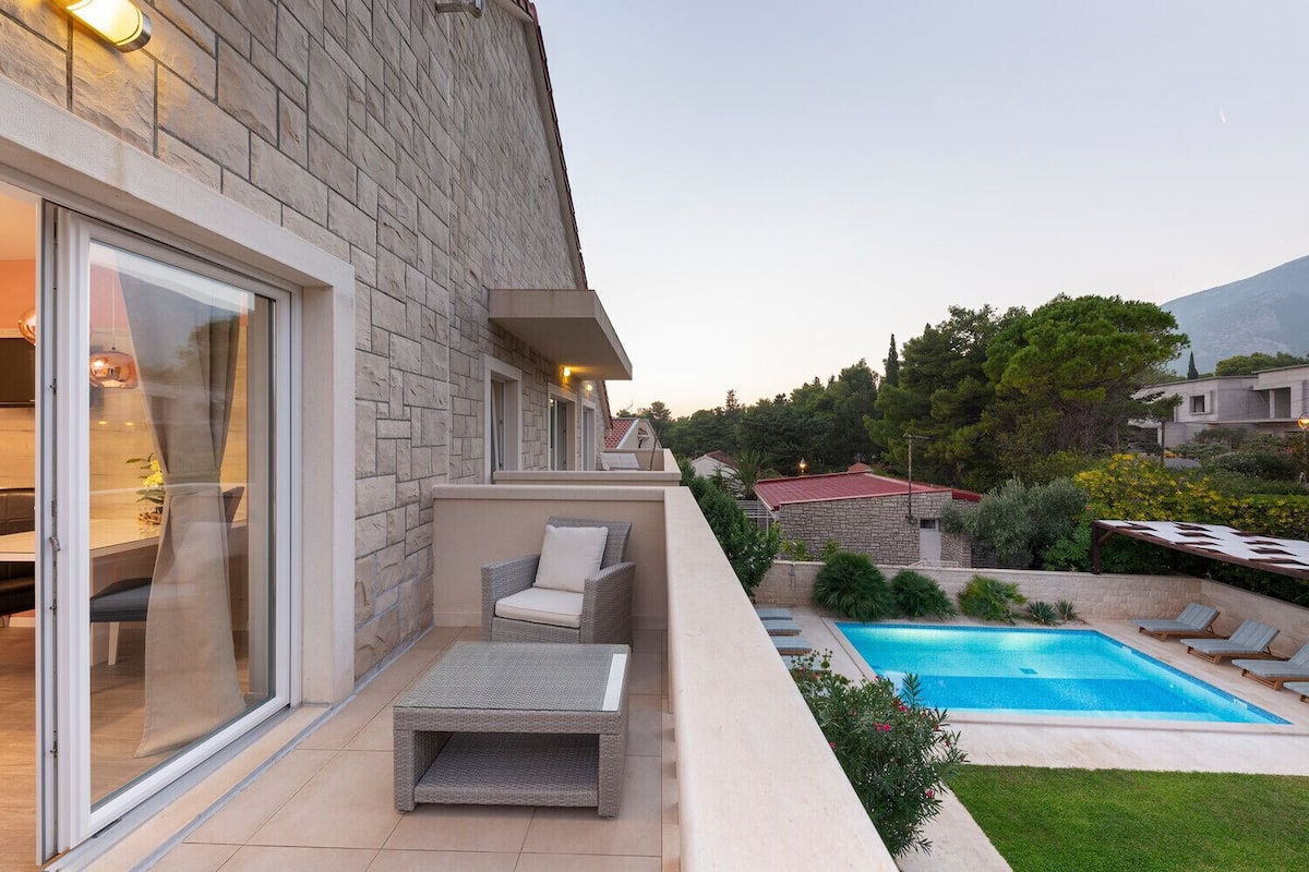 A modern outdoor living area with a pool, outdoor seating, and a view of the surrounding landscape.