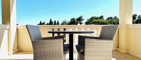 A covered outdoor seating area with a table and two wicker chairs.