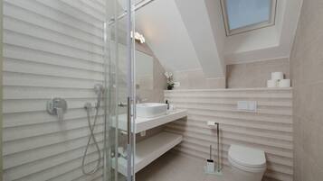 Une salle de bain moderne avec une douche à l’italienne en verre, un lavabo blanc et des toilettes.