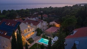 Zona residencial con casas, piscina y vista al mar al atardecer.