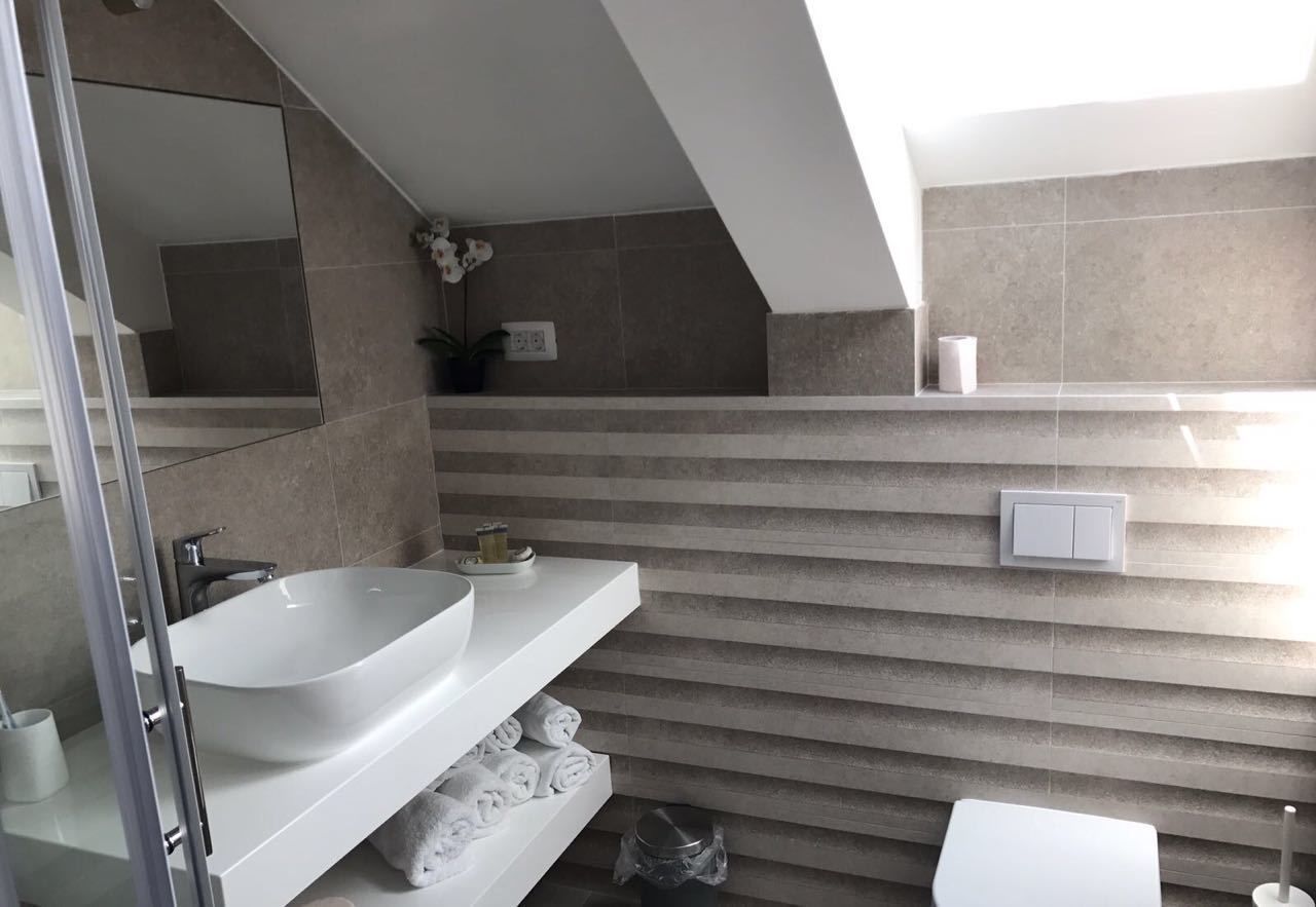 Une salle de bain moderne avec un grand lavabo blanc, une douche en verre et un porte-serviettes.