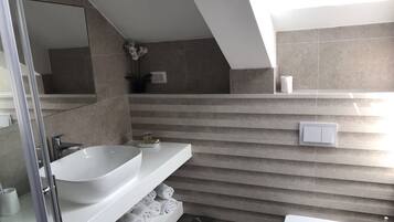 Une salle de bain moderne avec un grand lavabo blanc, une douche en verre et un porte-serviettes.