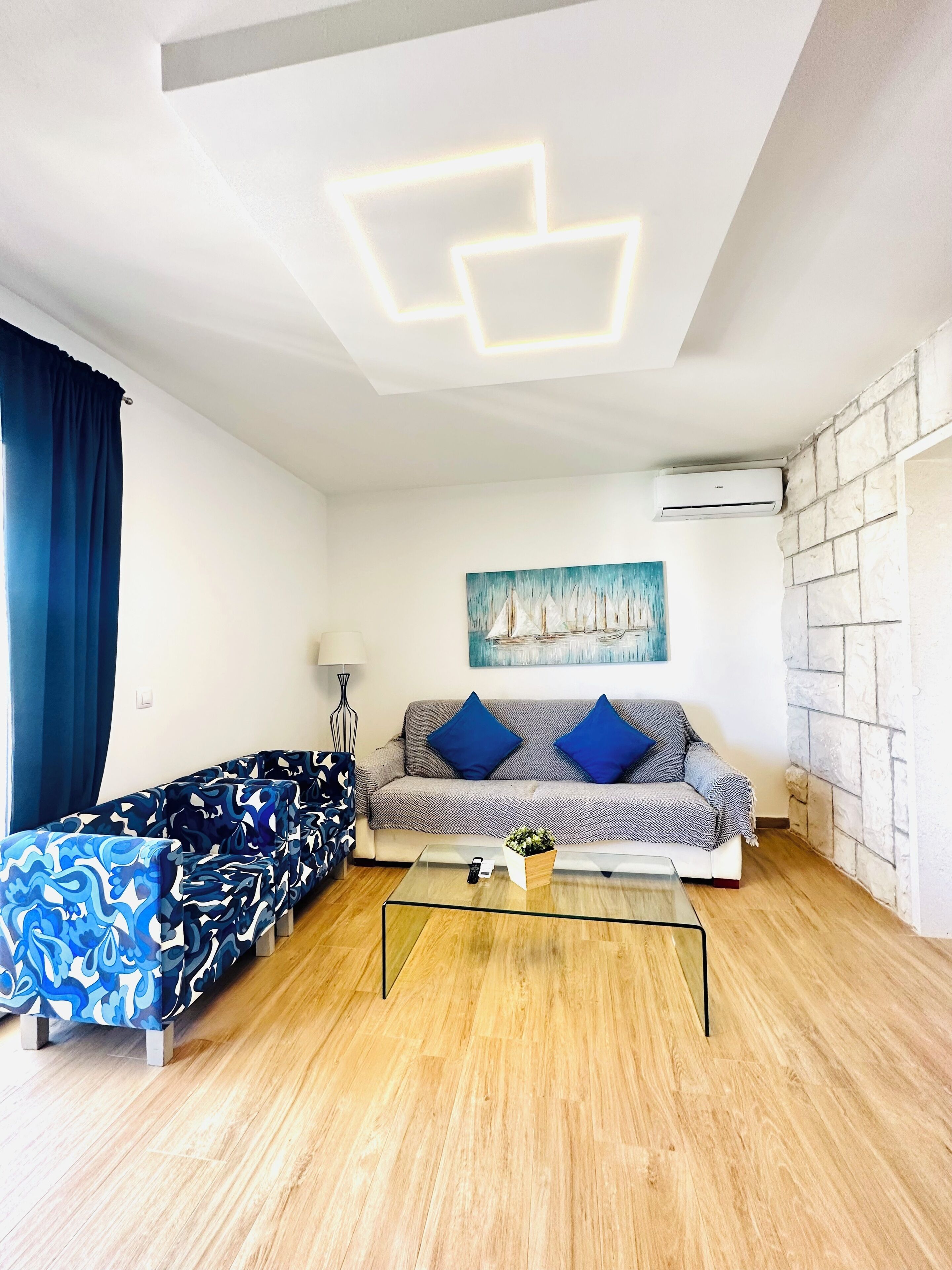 Una sala de estar moderna con un sofá, una mesa de centro de vidrio y un cuadro en la pared.