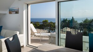 Un balcón con vista al mar, un sofá blanco y una mesa de comedor.