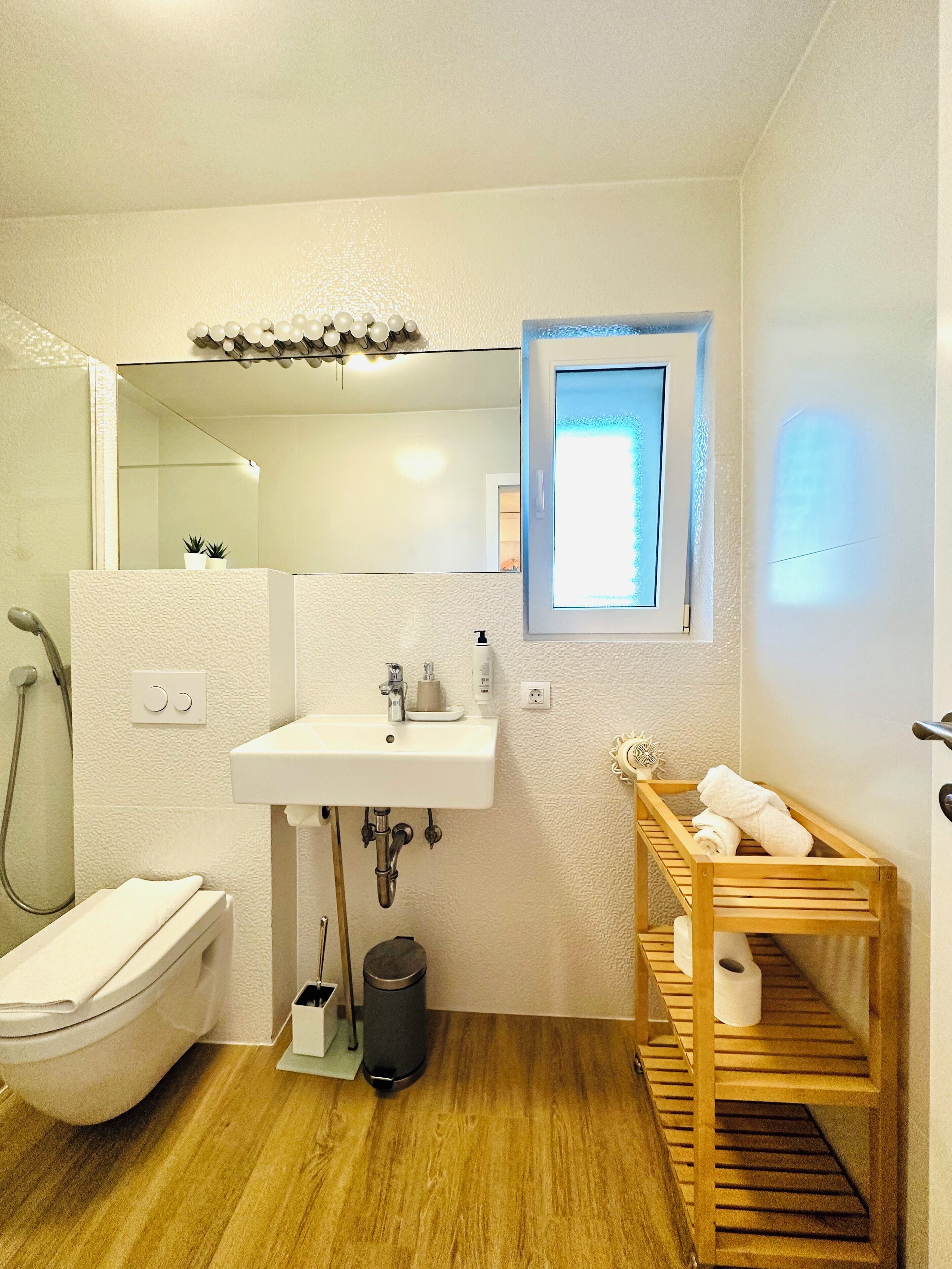 Un baño con inodoro, lavamanos, ducha y una pequeña ventana.