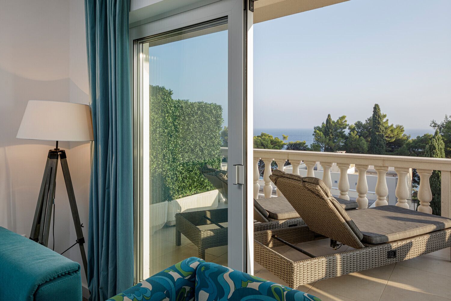 A balcony with wicker furniture, a lamp, and a view of the sea.