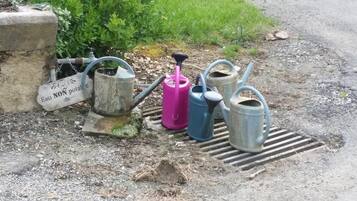 A water pump and several watering cans near a concrete structure with a sign reading "Eau NON potable".