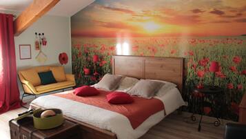 Un dormitorio con una cama de madera, un sillón amarillo, un jarrón con flores rojas y un mural en la pared con motivos de amapolas.