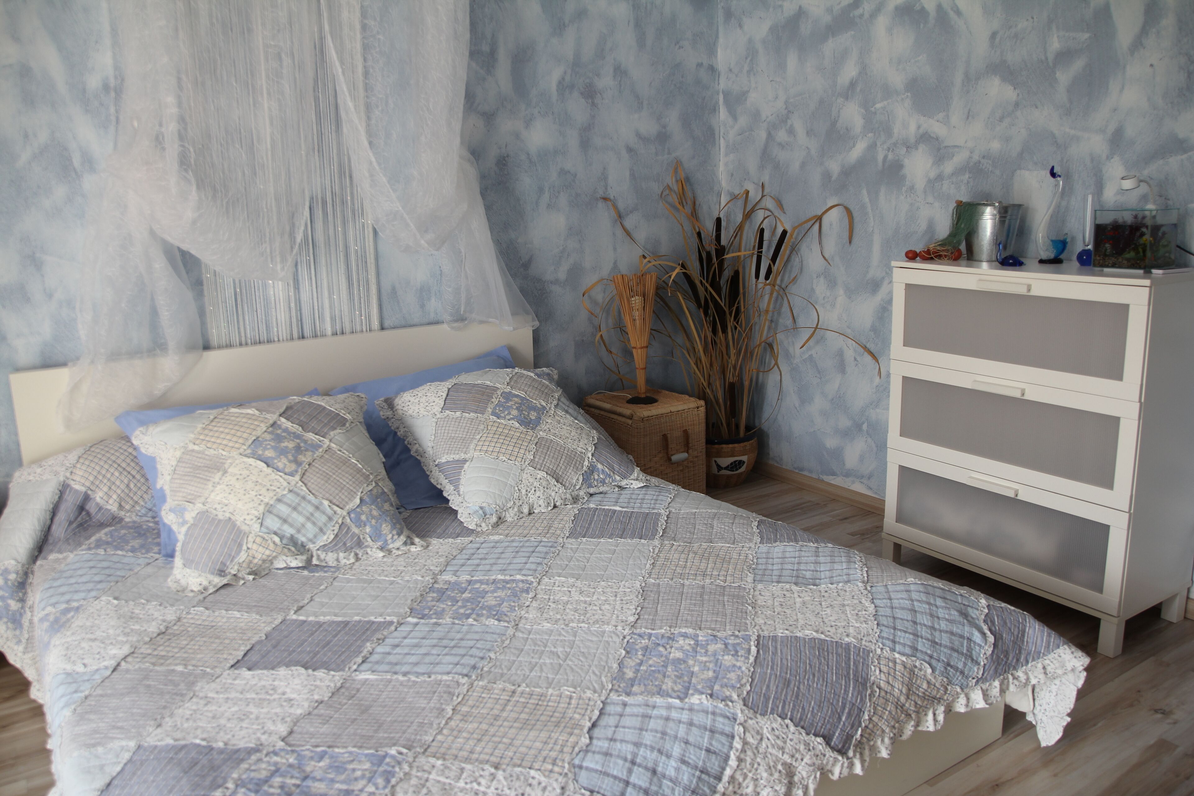 Un dormitorio con cama, mesita de noche, cómoda y pared con textura.
