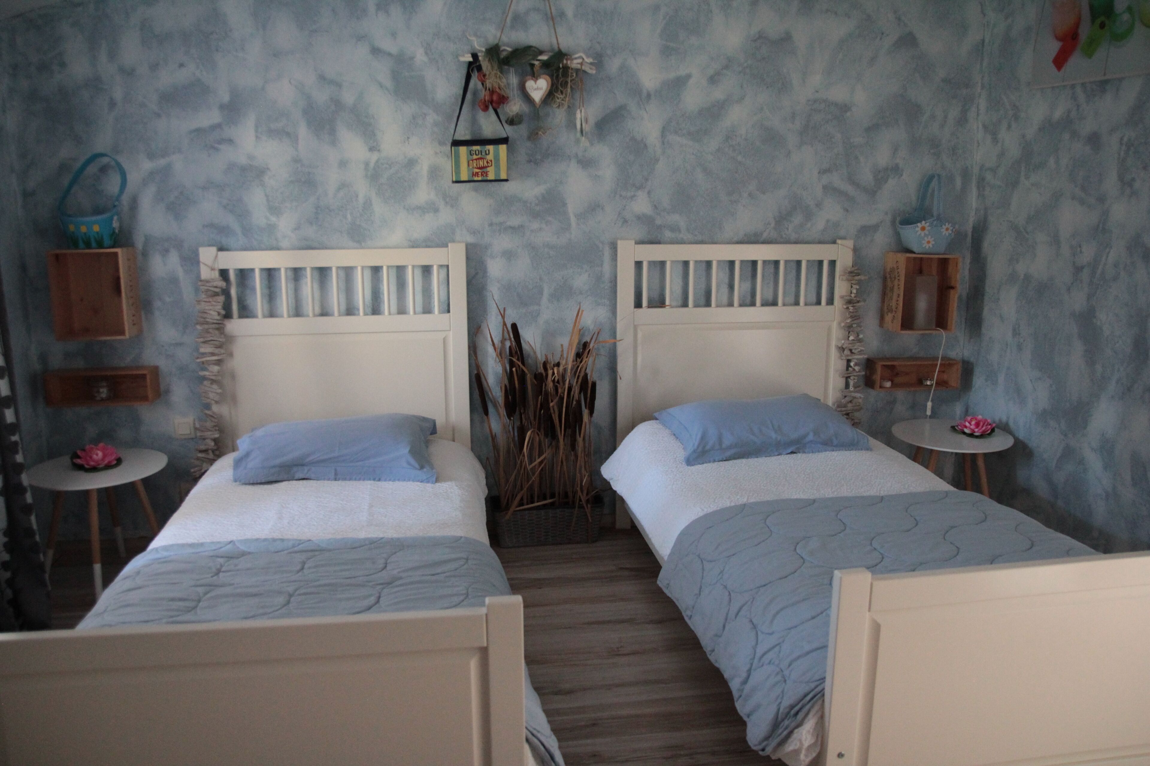 Ein Schlafzimmer mit zwei Betten, einem kleinen runden Tisch und einem an der Wand befestigten Regal.