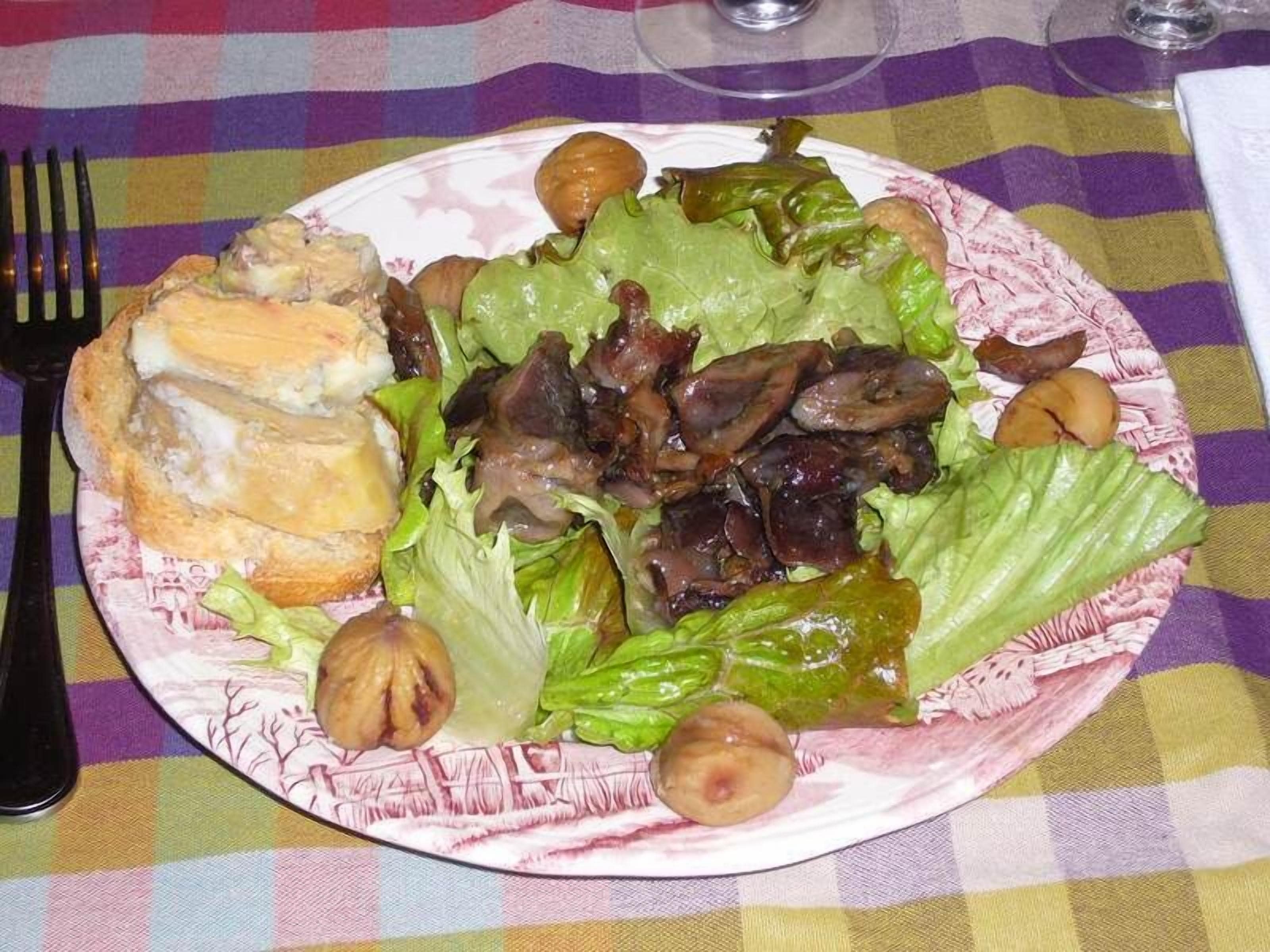 Un plato de comida con un sándwich, lechuga, champiñones y nueces sobre un mantel a cuadros.