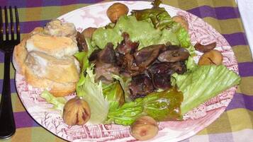 Un plato de comida con un sándwich, lechuga, champiñones y nueces sobre un mantel a cuadros.