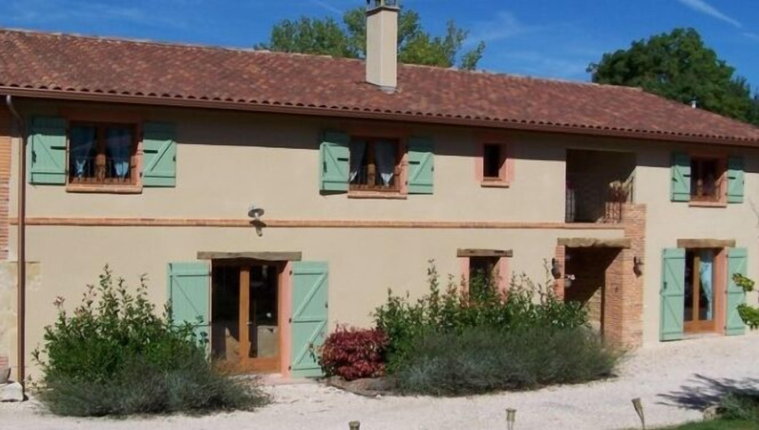 Un bâtiment à deux étages, doté d’un toit recouvert de tuiles, de nombreuses fenêtres avec volets et d’une entrée centrale.