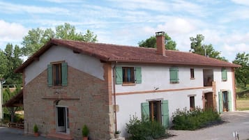 A two-story house with a sloped roof, green shutters, and a chimney.