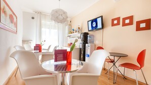 A modern, well-lit room with white furniture, a round table, and a TV mounted on the wall. - B&B Maricla (Verona)