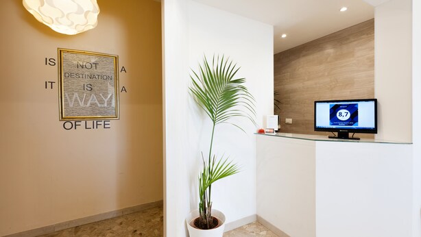 A reception area with a potted plant, a motivational quote on the wall, and a computer monitor displaying a website. - B&B Maricla (Verona)