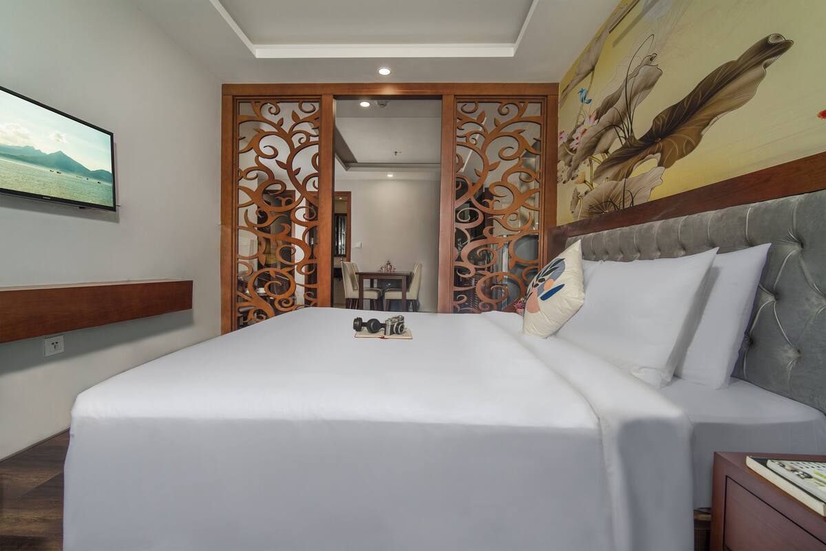 A hotel room with a large bed, a television on the wall, and a decorative screen door.