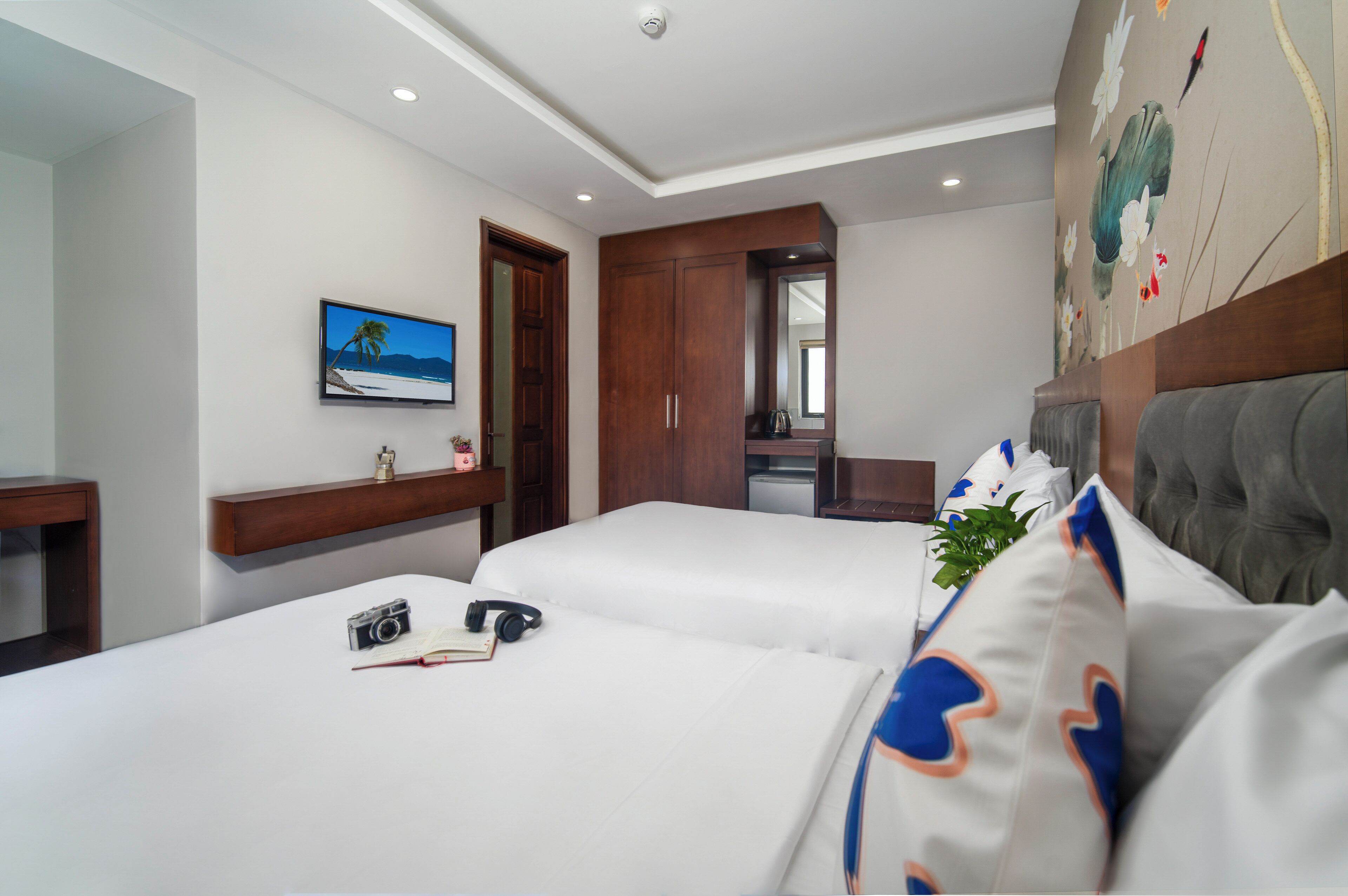 Habitación de hotel con dos camas, un televisor, un armario de madera y un cuadro en la pared.