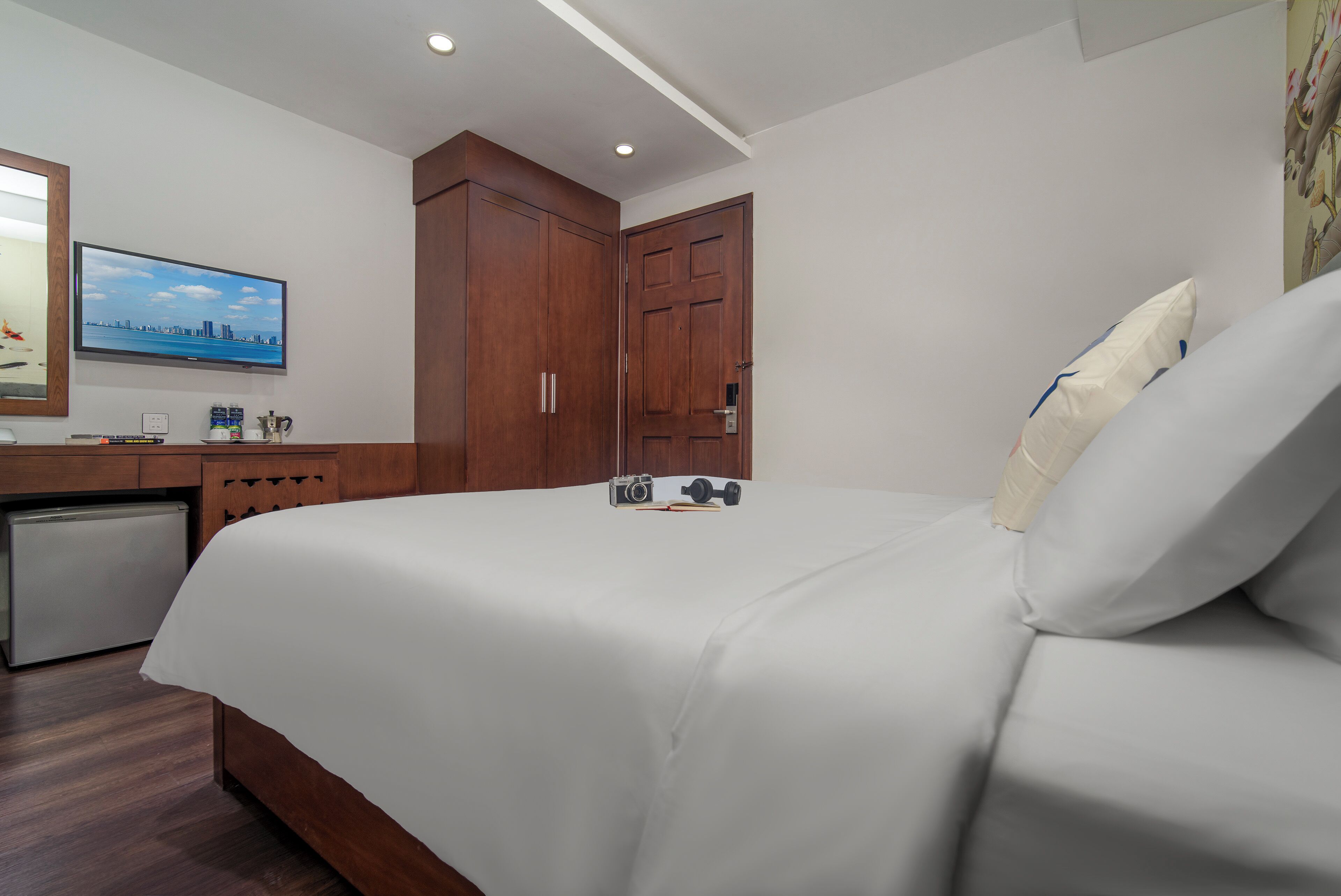 A hotel room with a bed, a desk, a television, and a wardrobe.