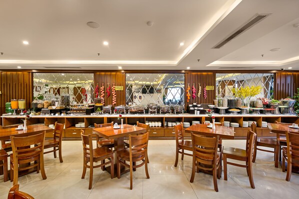 A restaurant with wooden tables and chairs, a buffet counter with various food items, and a view of the street outside.