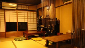 Una habitación japonesa tradicional con suelo de tatami, una mesa de madera baja, cojines y puertas correderas.