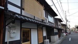 Un edificio japonés tradicional con puerta de madera, un pequeño porche y un contador de servicios públicos en la pared.
