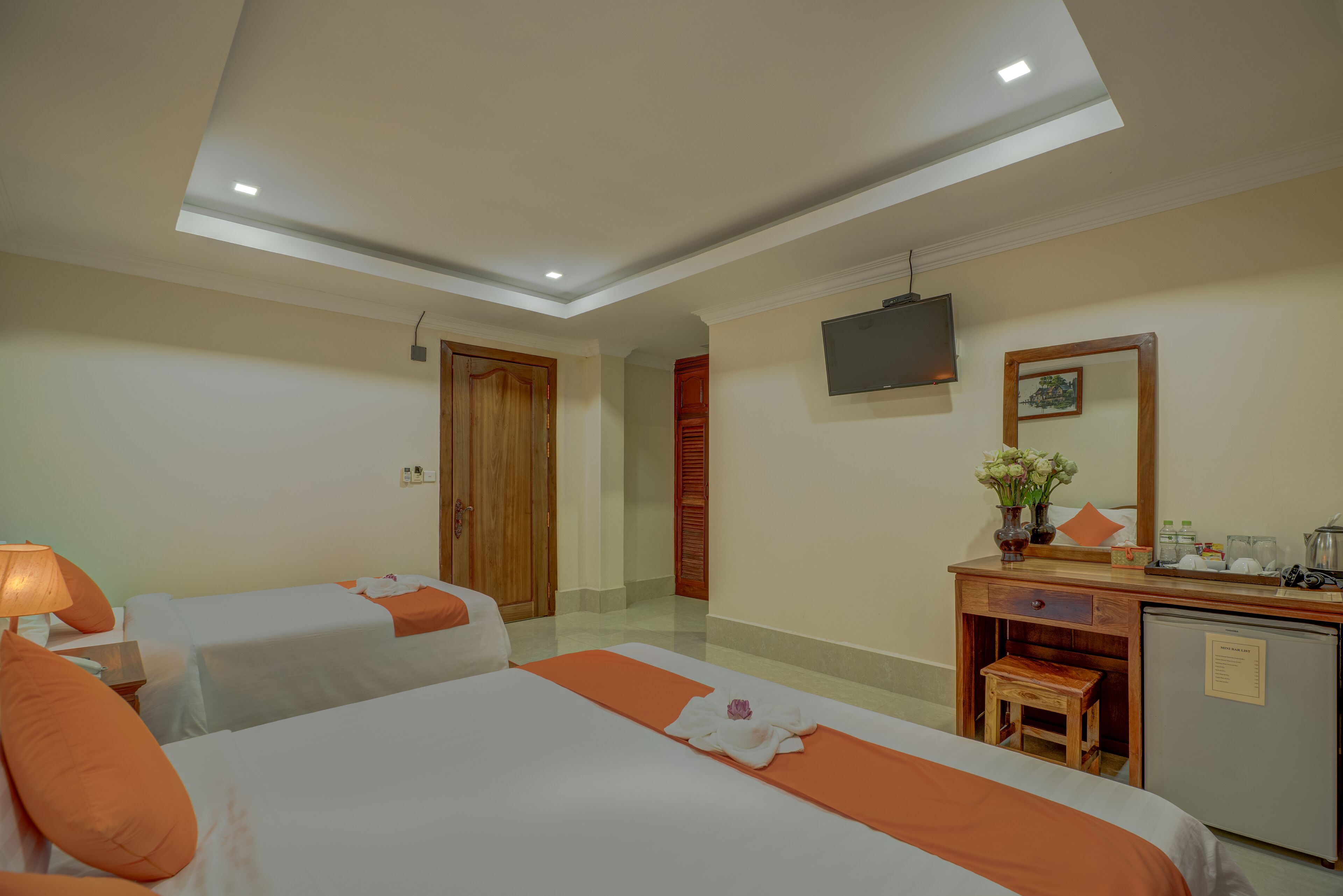 Une chambre d’hôtel avec deux lits, un bureau, une télévision et un petit réfrigérateur.