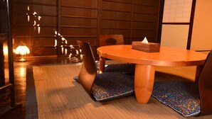 Una habitación tradicional japonesa con suelo de tatami, una mesa de madera baja y un muro con puertas correderas shoji.
