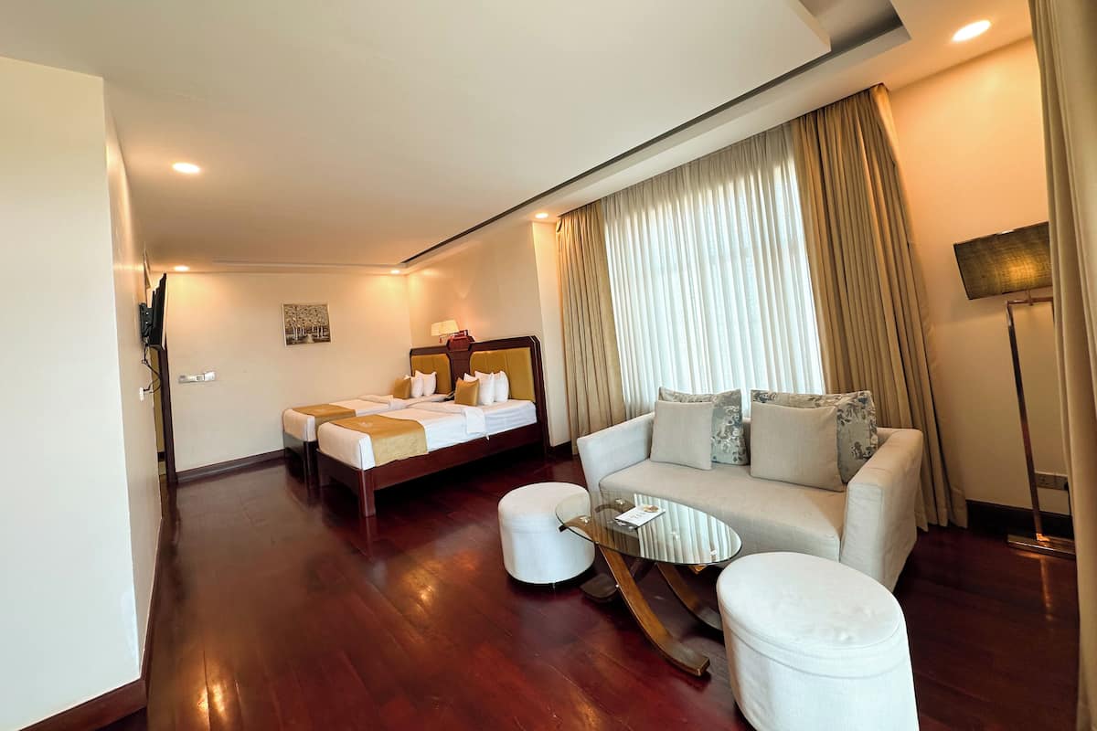 Une chambre d’hôtel avec un lit, un canapé, une table basse et un téléviseur.
