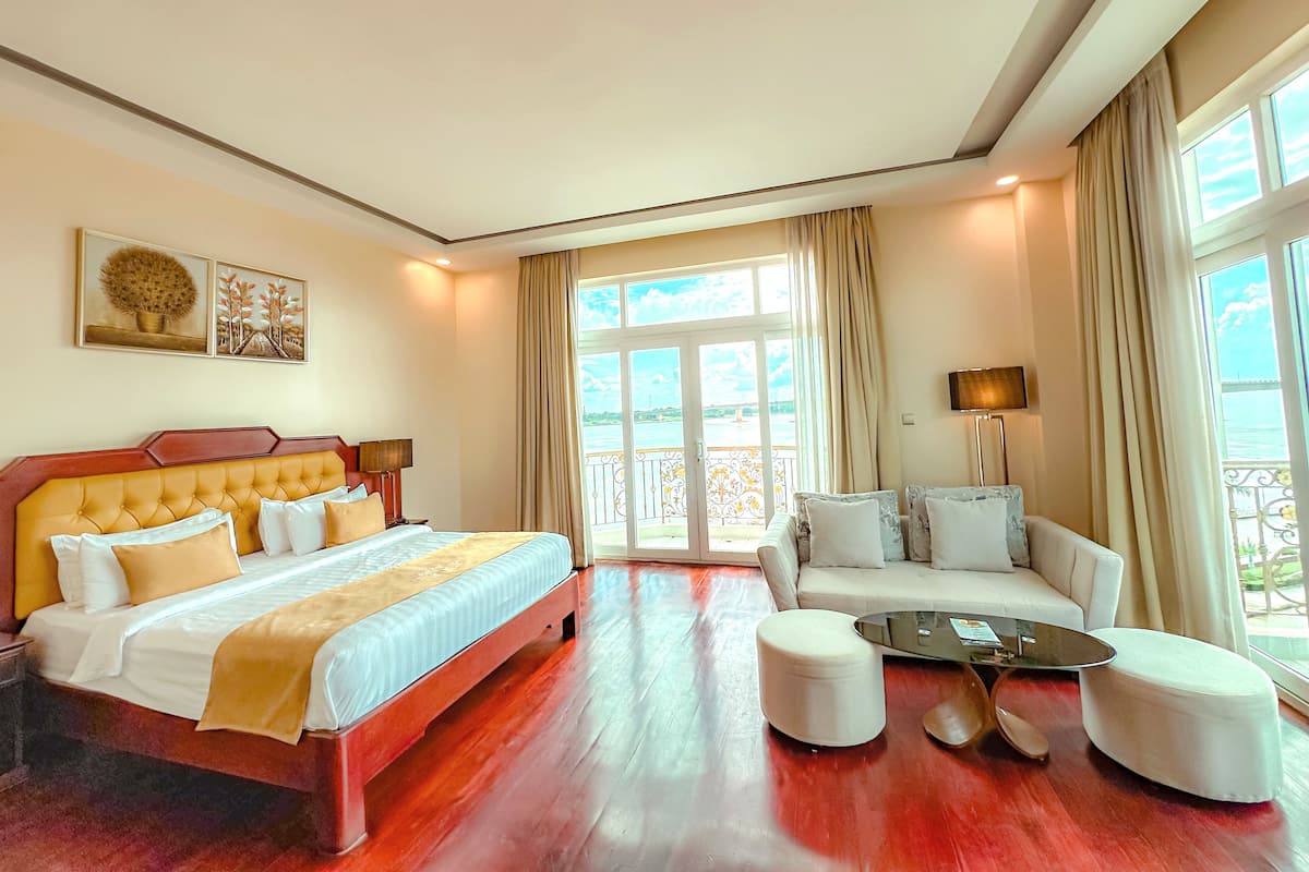 Une chambre d’hôtel avec un grand lit, un canapé, une table basse et un balcon avec vue.